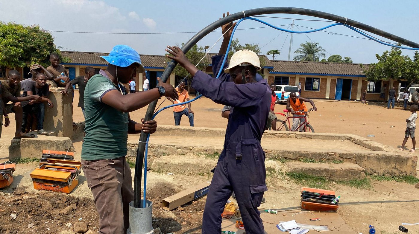 SINES - técnicos descendiendo una bomba sumergible Grundfos en una perforación de aldea en Burundi